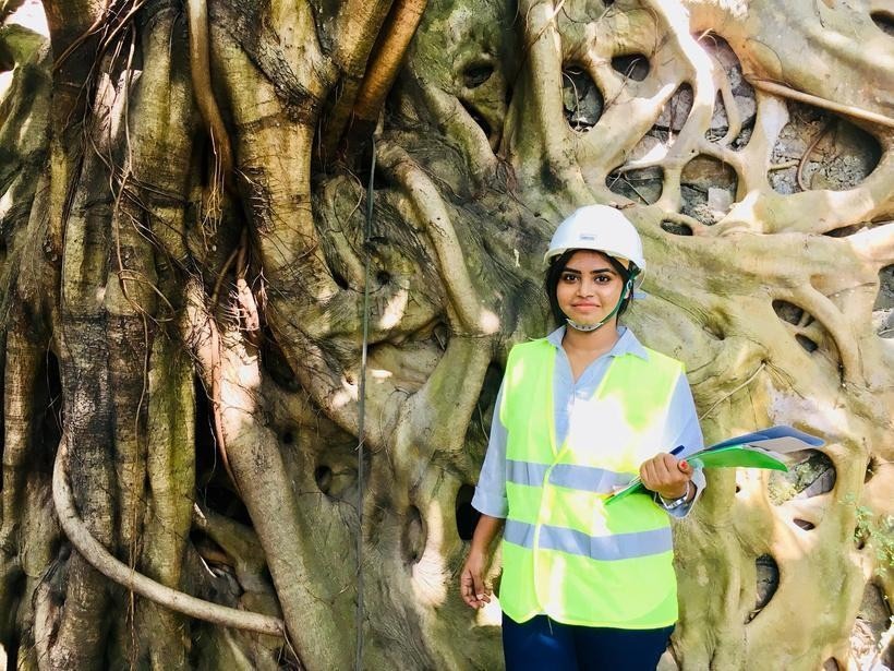 Sanali conducting ecological fieldwork beside a mature tree